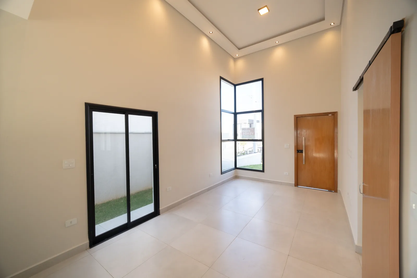 O pé-direito alto e as aberturas da sala, vistos em direção à entrada.