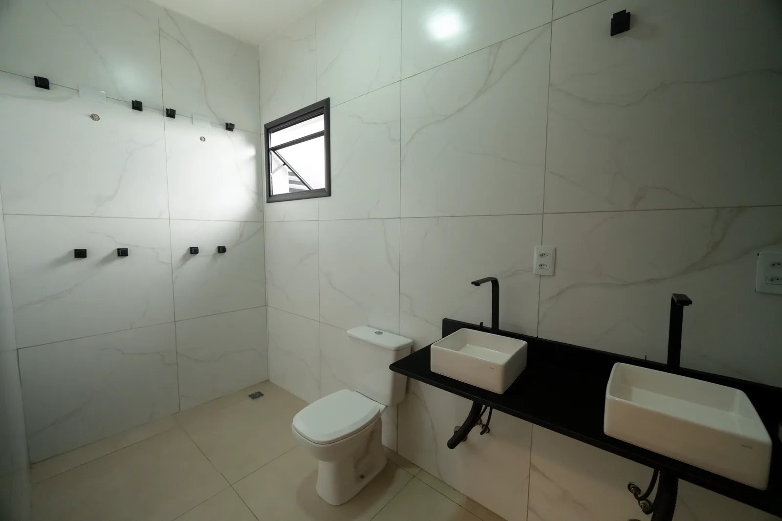 O banheiro da suíte com bancada de duas cubas.