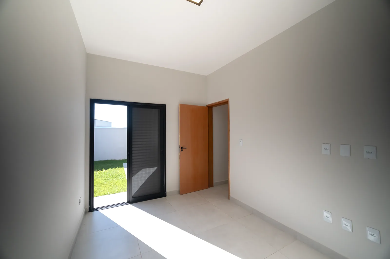 O dormitório 2 / sala de TV com porta de vidro para o jardim.